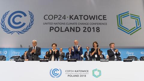 15.12.2018, Polen, Katowice: Michal Kurtyka (M), Präsident der UN-Klimakonferenz COP24, und weitere Teilnehmer des Klimagipfels freuen sich über den Beschluss des Kompromisses beim Weltklimagipfel.