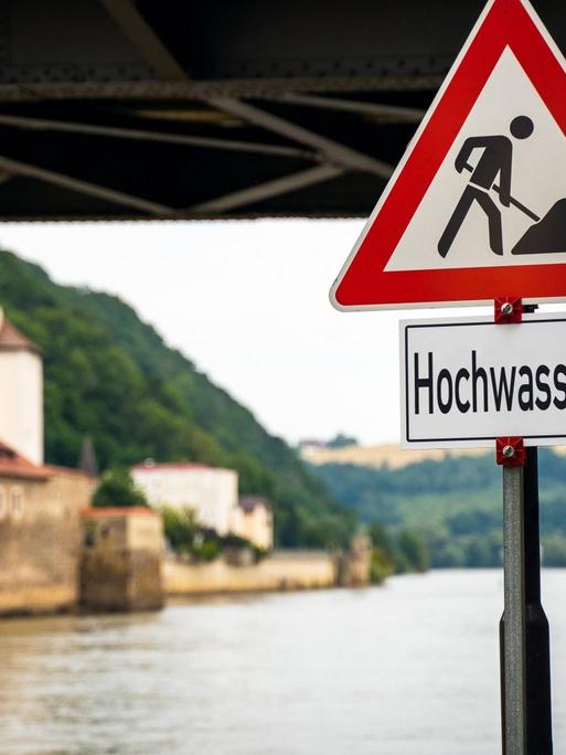 Hochwasser in Passau: Fluss mit Straßenschild, Brücke und Häuser.