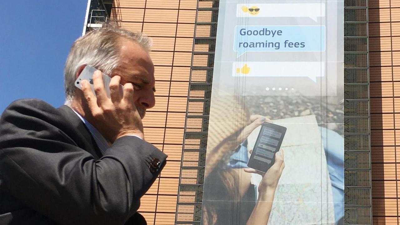 Mann telefoniert vor Hochhaus mit seinem Smartphone