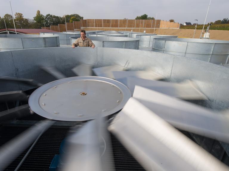 Ein Mitarbeiter steht in Insheim (Rheinland-Pfalz) in einem Geothermiekraftwerk neben einem großen Ventilator.