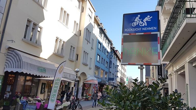 In der Karlsruher Fußgängerzone ermahnt ein Schild Radfahrer, langsam zu fahren