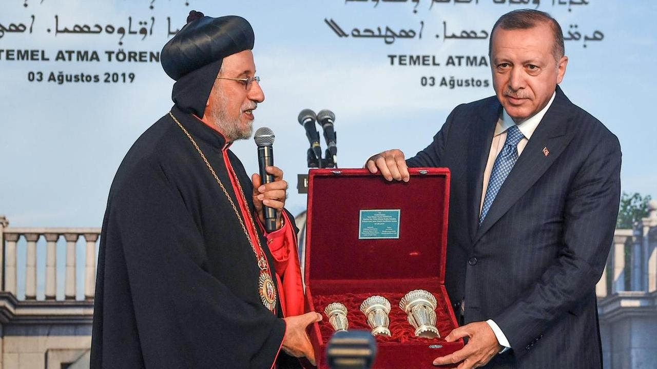 Der syrisch-orthodoxe Patriarch Yusuf Cetin (links) überreicht Präsident Erdogan bei der Grundsteinlegung für die erste christliche Kirche seit 1923 ein Geschenk.