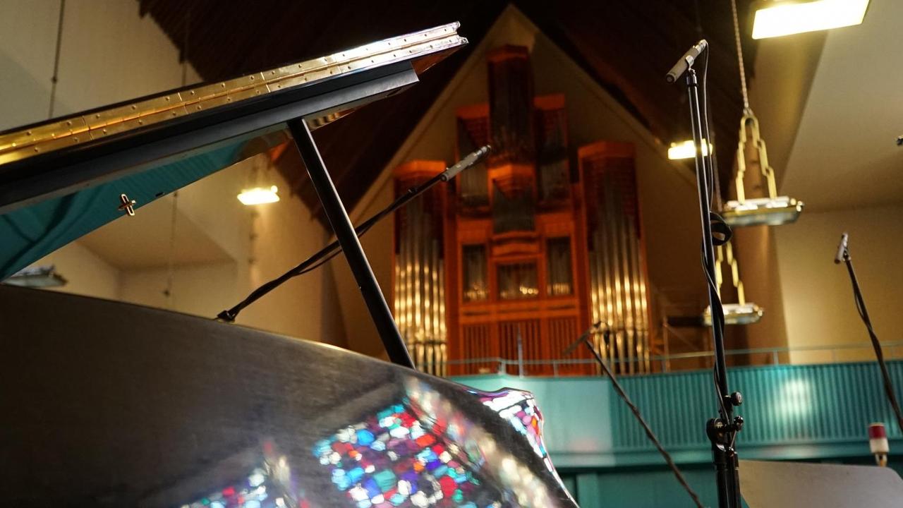 Ein Flügel in einer Kirche, im Hintergrund ist eine Orgel sichtbar.