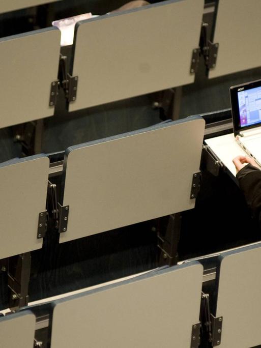 Eine Studentin sitzt allein in einem Hörsaal am Laptop