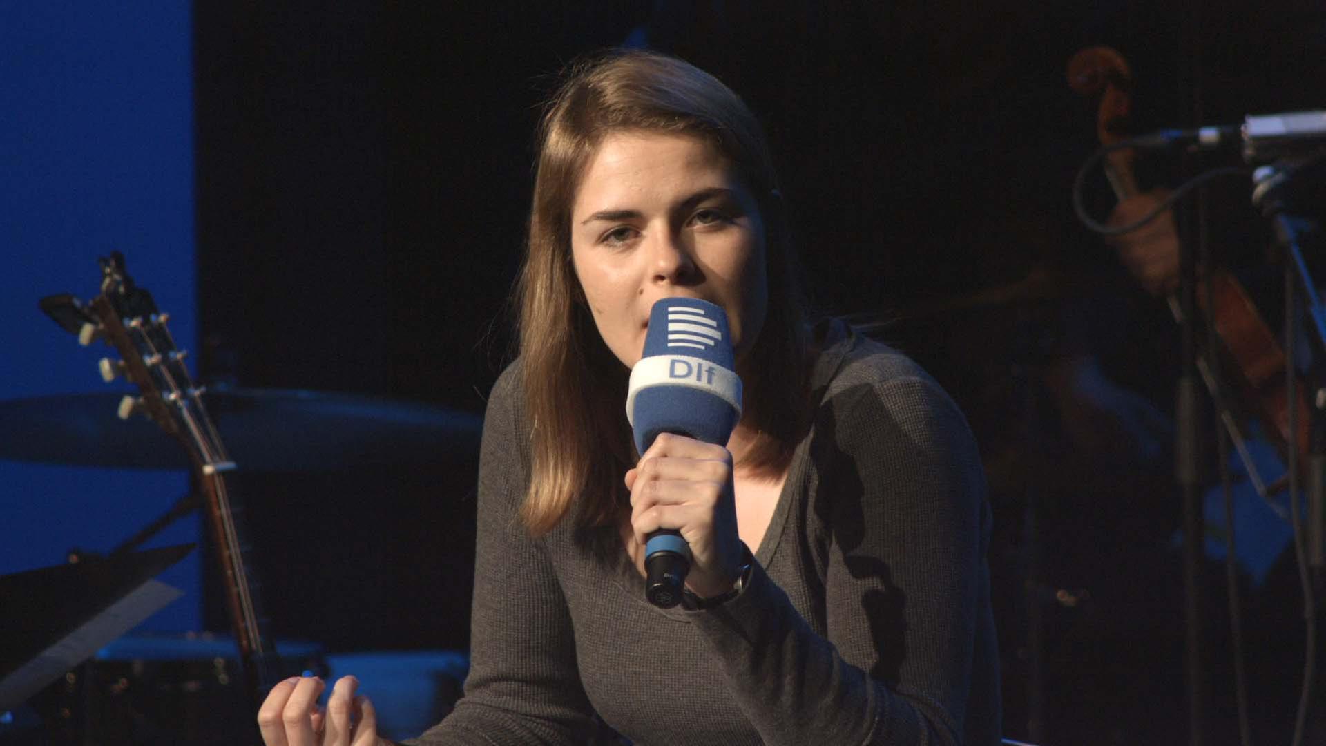 Die Schweizerin Hazel Brügger mit einem Mikrofon bei Ihrem Stand Up-Auftritt.