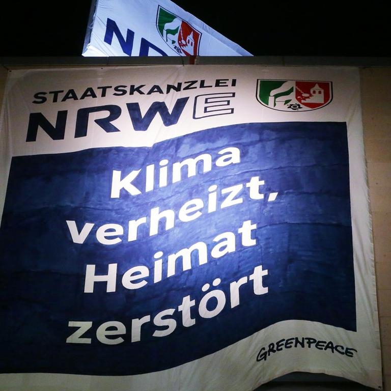 Ein Banner mit der Aufschrift "Staatskanzlei NRWE: Klima verheizt, Heimat zerstört"