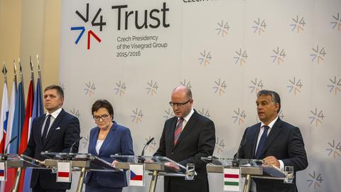 Der slowakische Premierminister Robert Fico, Polens Premierministerin Ewa Kopacz, der tschechische Premierminister Bohuslav Sobotka und der ungarische Premierminister Viktor Orban stehen in einer Reihe nebeneinander an Mikrofonen.