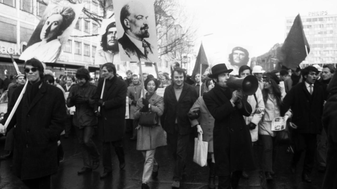 Schwarz-weiß-Fotografie von 1968: Sie zeigt Studenten während einer Demonstration, die Schilder mit den Porträts von Lenin, Che Guevara und Rosa Luxemburg in die Höhe halten.