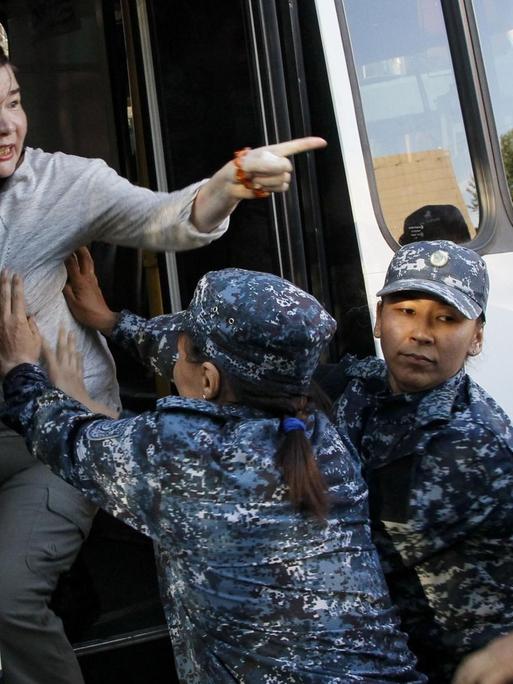 Eine Frau wird während einer Demonstration gegen die kasachische Regierung am 6. Juli in der Hauptstadt Nur-Sultan verhaftet. Polizeibeamte schieben eine Frau in einen Bus.