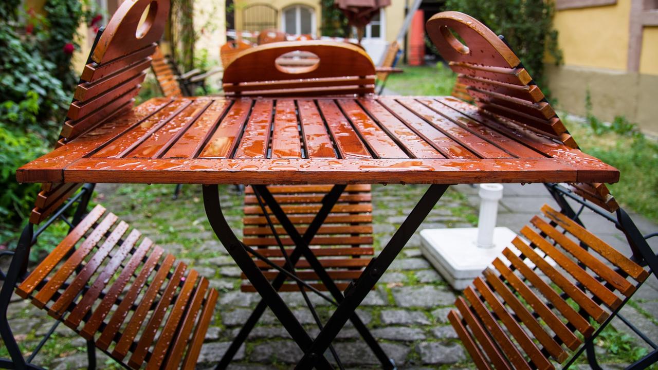 Blick auf regennasse Holzstühle und einen Tisch