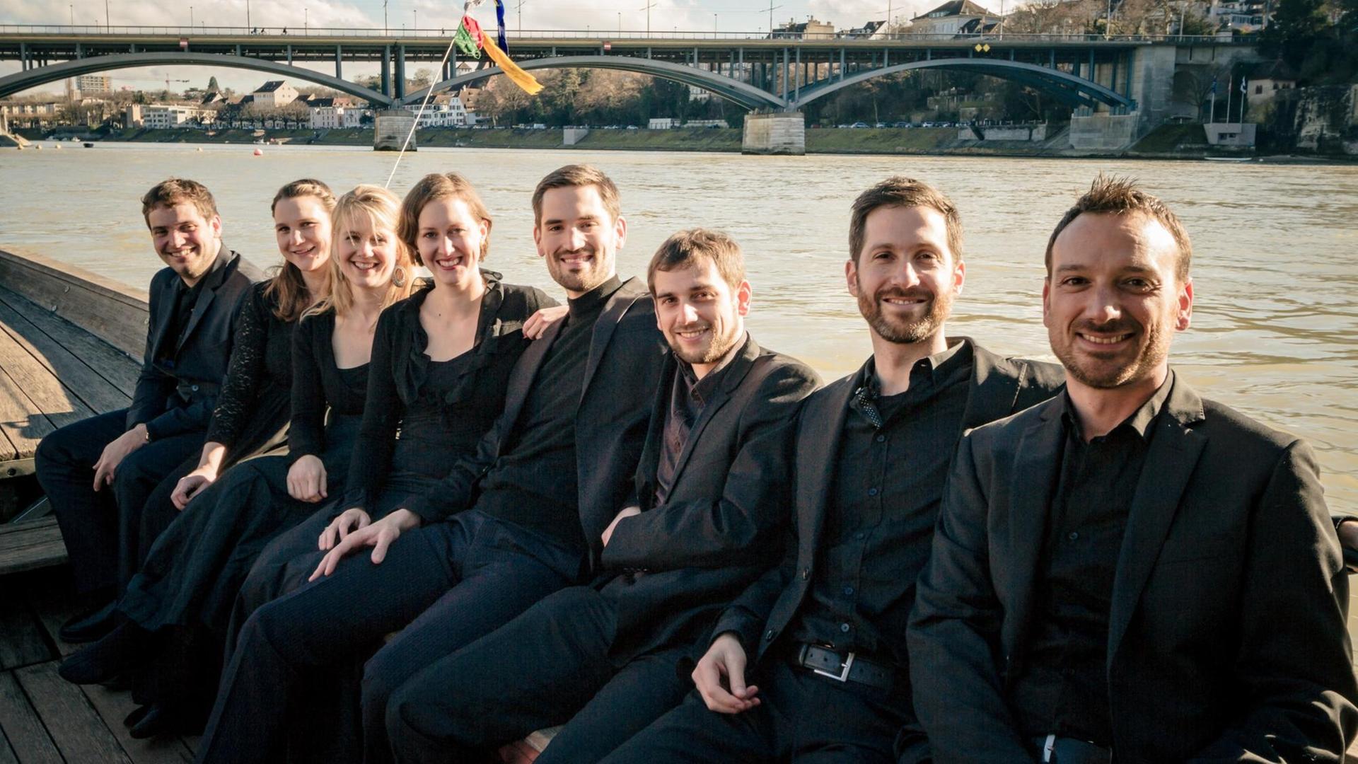 Das Ensemble Voces Suaves in Konzertkleidung aufgereiht auf einem Boot auf einem Fluss