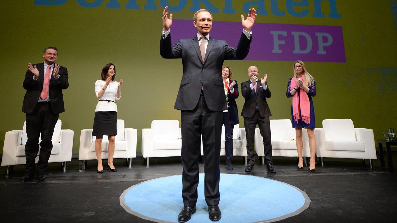 Christian Lindner, der Vorsitzende der FDP, winkt in Stuttgart im Opernhaus beim traditionellen Dreikönigstreffen der Partei nach seiner Rede ins Publikum. Im Hintergrund wird das neue Parteilogo präsentiert.