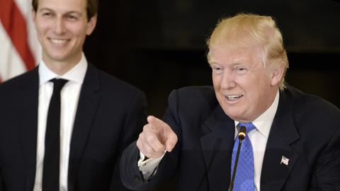 US-Präsident Donald Trump spricht und lacht dabei. Im Hintergrund ist sein Schwiegersohn Jared Kushner zu sehen.