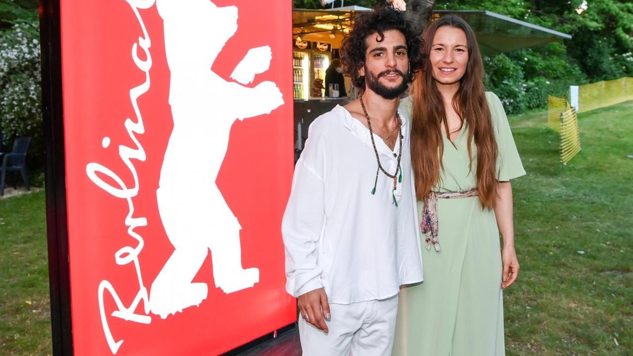 Die Regisseurin Anne Zohra Berrached und der libanesische Schauspieler Roger Azar. Ein Mann und eine Frau stehen in sommerlicher Abenkleidung in einem Freiluftkino. Die Regisseurin Anne Zohra Berrached und der libanesische Schauspieler Roger Azar. Ein Mann und eine Frau stehen in sommerlicher Abenkleidung in einem Freiluftkino.