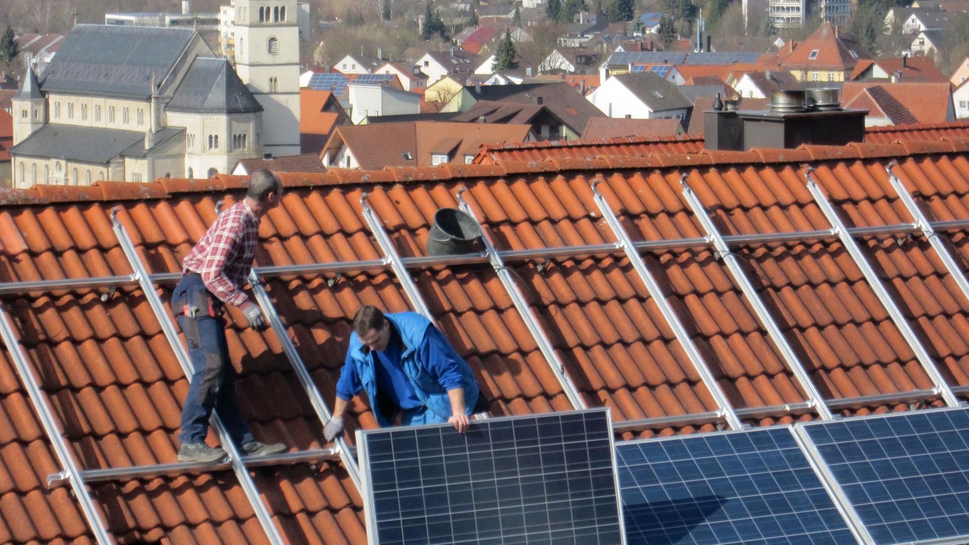 Arbeiter installieren Solarzellen auf einem Dach