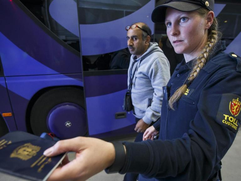 Eine norwegische Polizistin kontrolliert den Pass eines Flüchtlings.