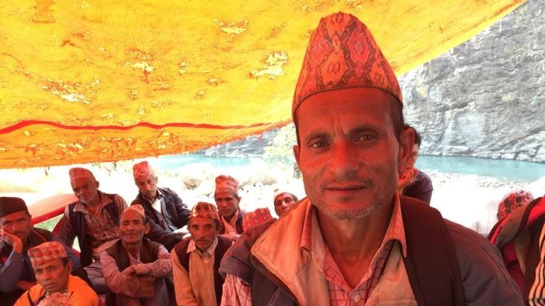 Sie sehen den Nepalesen Janak Bahardur mit einer bunten Mütze unter einem gelben Sonnensegel.