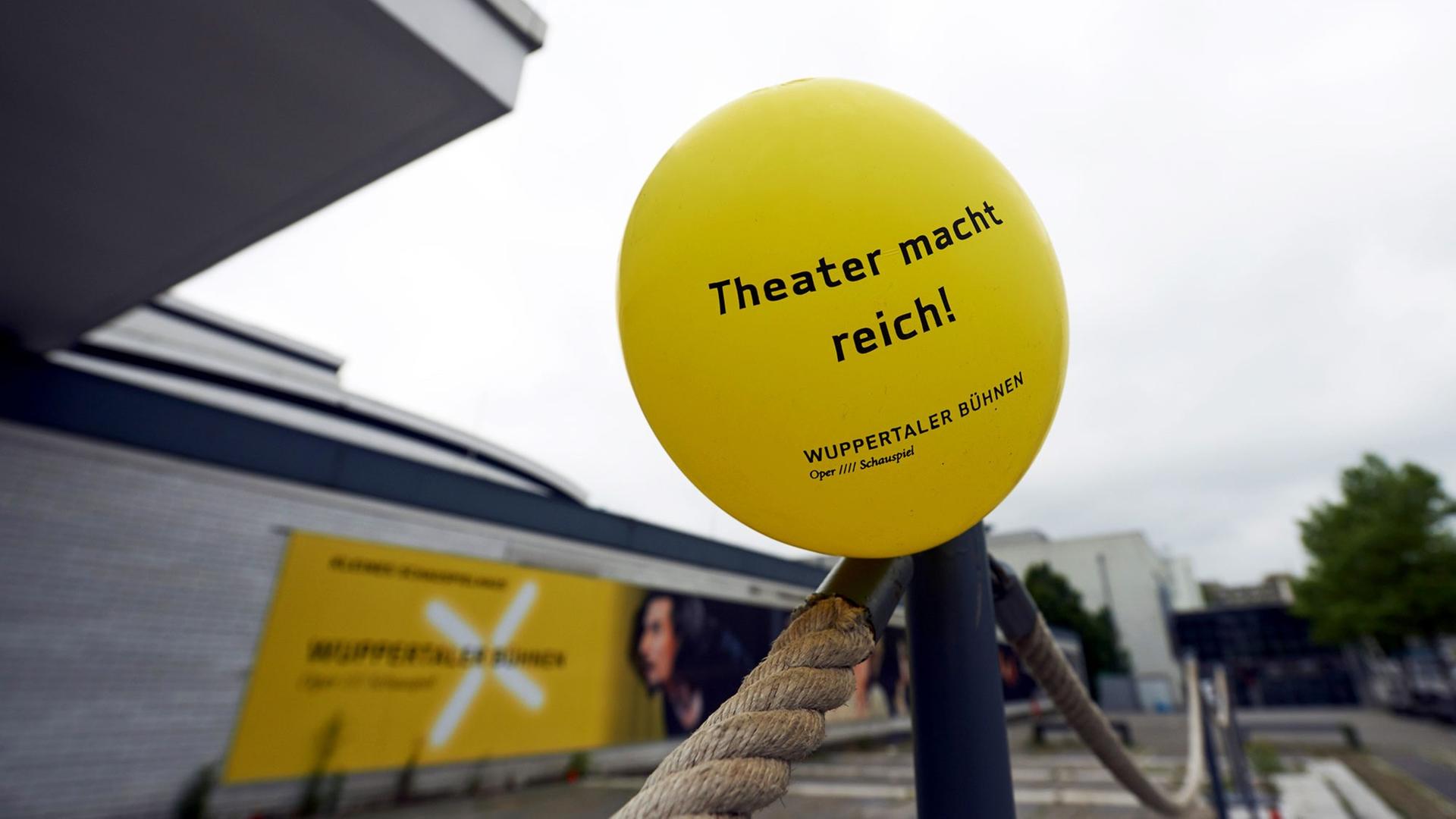 Ein Luftballon mit der Aufschrift "Theater macht reich!" vor dem geschlossenen Schauspielhaus Wuppertal.