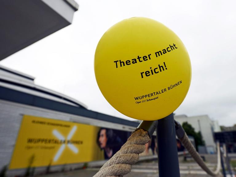 Ein Luftballon mit der Aufschrift "Theater macht reich!" vor dem geschlossenen Schauspielhaus Wuppertal.