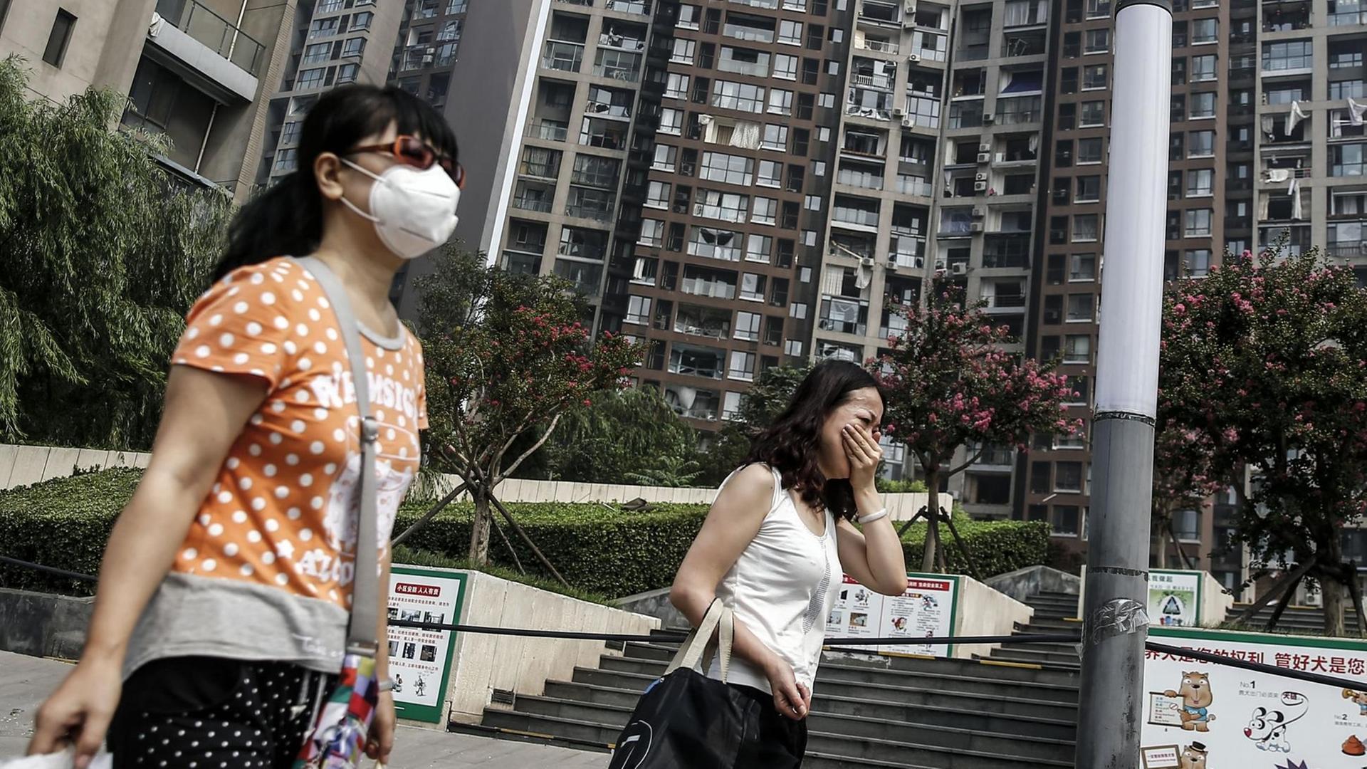 Anwohnerinnen verlassen mit Atemschutz und Gepäck ihre Wohngebäude in Tianjin. Anwohnerinnen verlassen mit Atemschutz und Gepäck ihre Wohngebäude in Tianjin.
