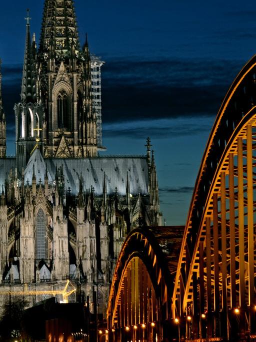 Der angestrahlte Kölner Dom, davor die Hohenzollernbrücke in Köln.