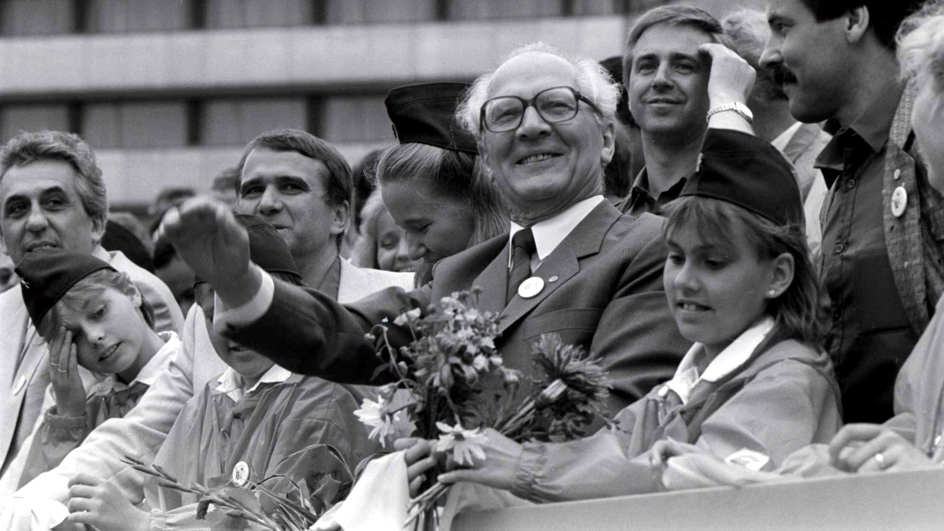 Erich Honecker (Mitte), Generalsekretär des ZK der SED und Vorsitzender des Staatsrates der DDR, Egon Krenz (l) und Eberhard Aurich (r) mit Pionieren auf der Ehrentribüne bei VIII. Pioniertreffen im August 1988 in Karl-Marx-Stadt.