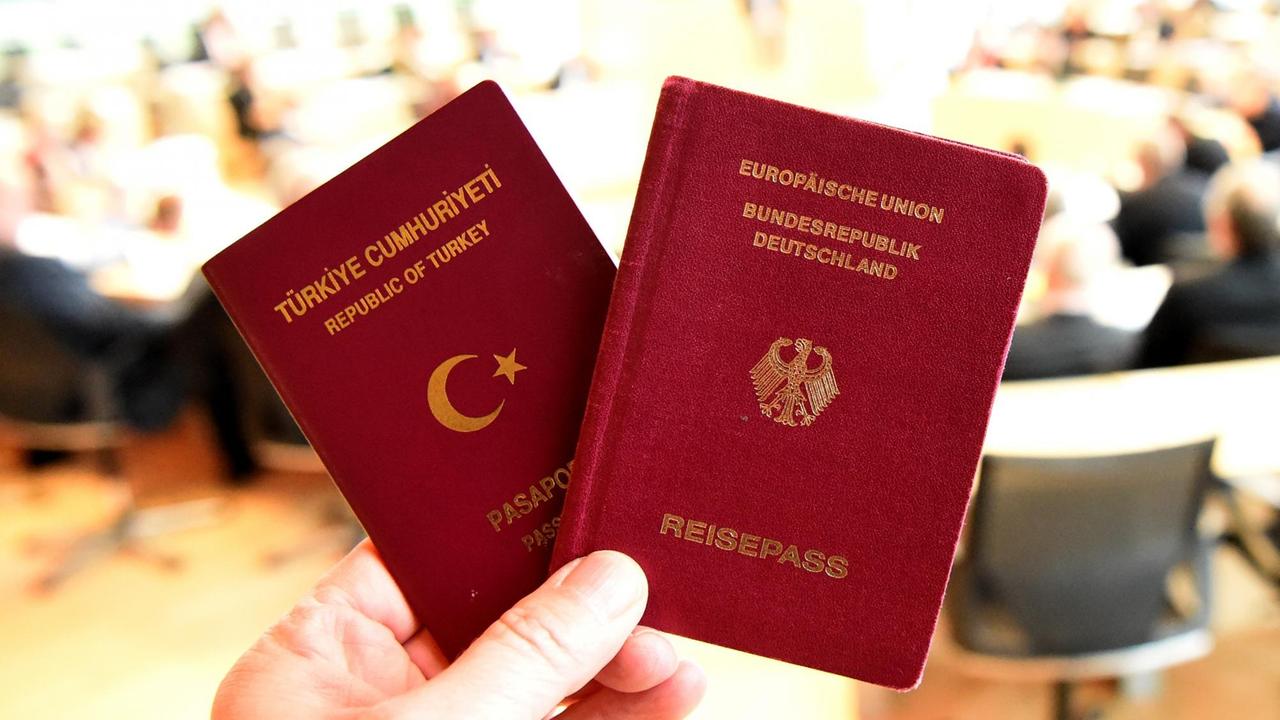 Ein deutscher und ein türkischer Pass werden am 15.12.2016 während der Landtagssitzung in Kiel (Schleswig-Holstein) in die Kamera gehalten. Das Thema doppelte Staatsbürgerschaft wird die Parlamentarier in ihrer Sitzung am Freitag (16.12.2016) beschäftigen. 