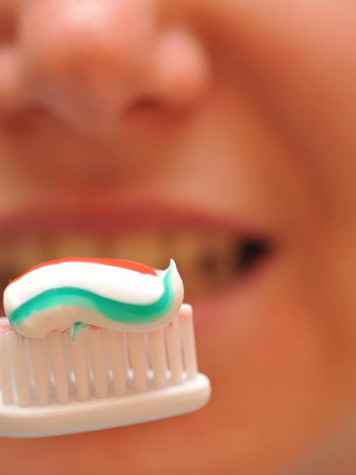 Eine Zahnbürste mit Zahnpasta vor einem Mund
