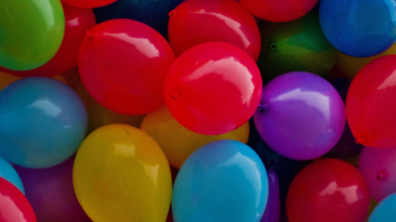 Viele bunte Luftballons liegen nebeneinander.