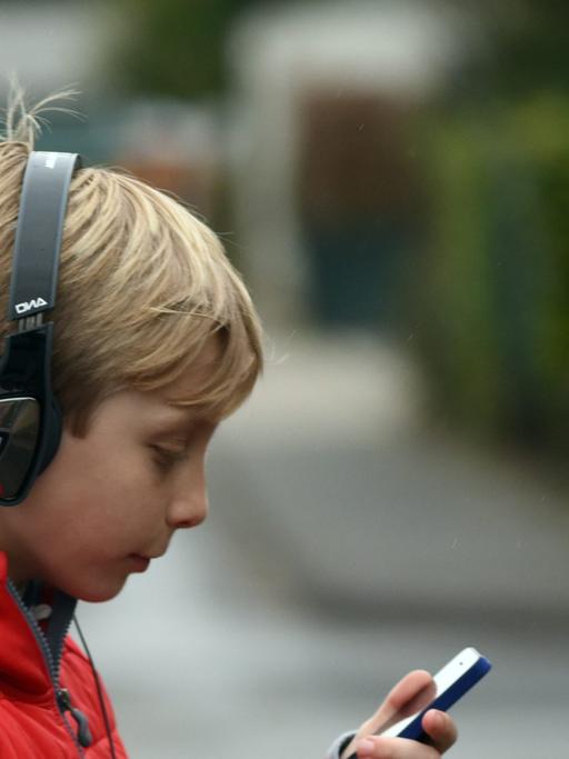 Ein Junge spaziert mit Kopfhörern und iPhone.