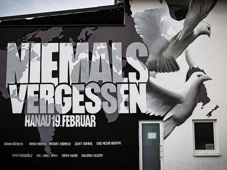 Ein Graffiti an einer Hauswand in Hanau zeigt eine Weltkarte, die Namen von neun der zehn Ermordeten, zwei weiße Tauben und die Worte: Niemals vergessen, Hanau 19. Februar