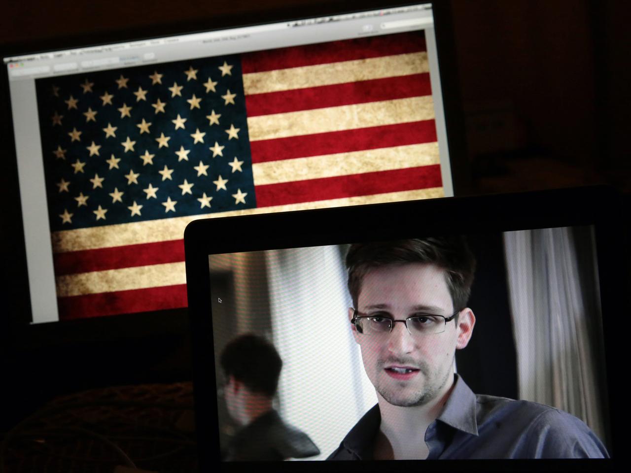 Edward Snowden auf einem Bildschirm vor einer US-Flagge