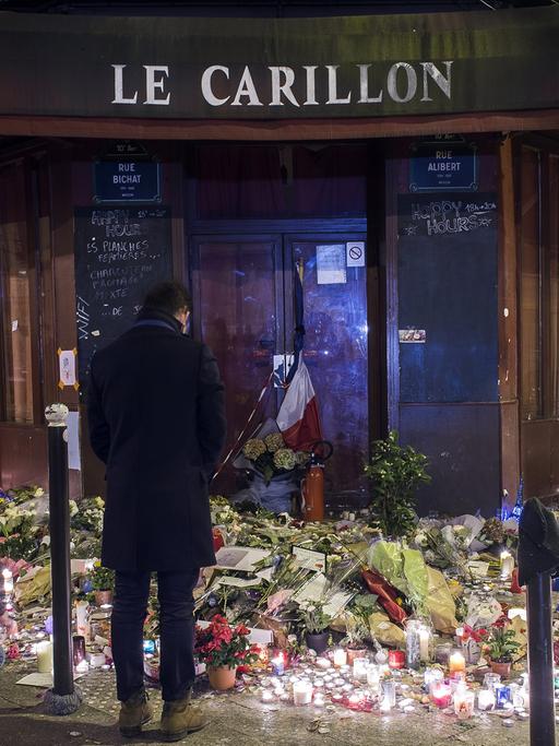 Zwei Männer und Blumen erinnern vor dem Pariser Café Le Carillon an die Attentatsserie.