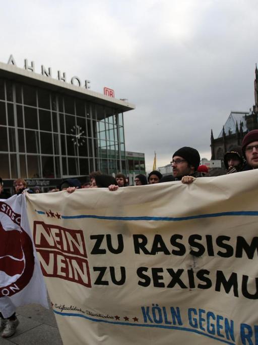 Demonstranten mit Transparenten vor dem Hauptbahnhof, darauf zu lesen "Nein zu Rassismus, nein zu Sexismus".