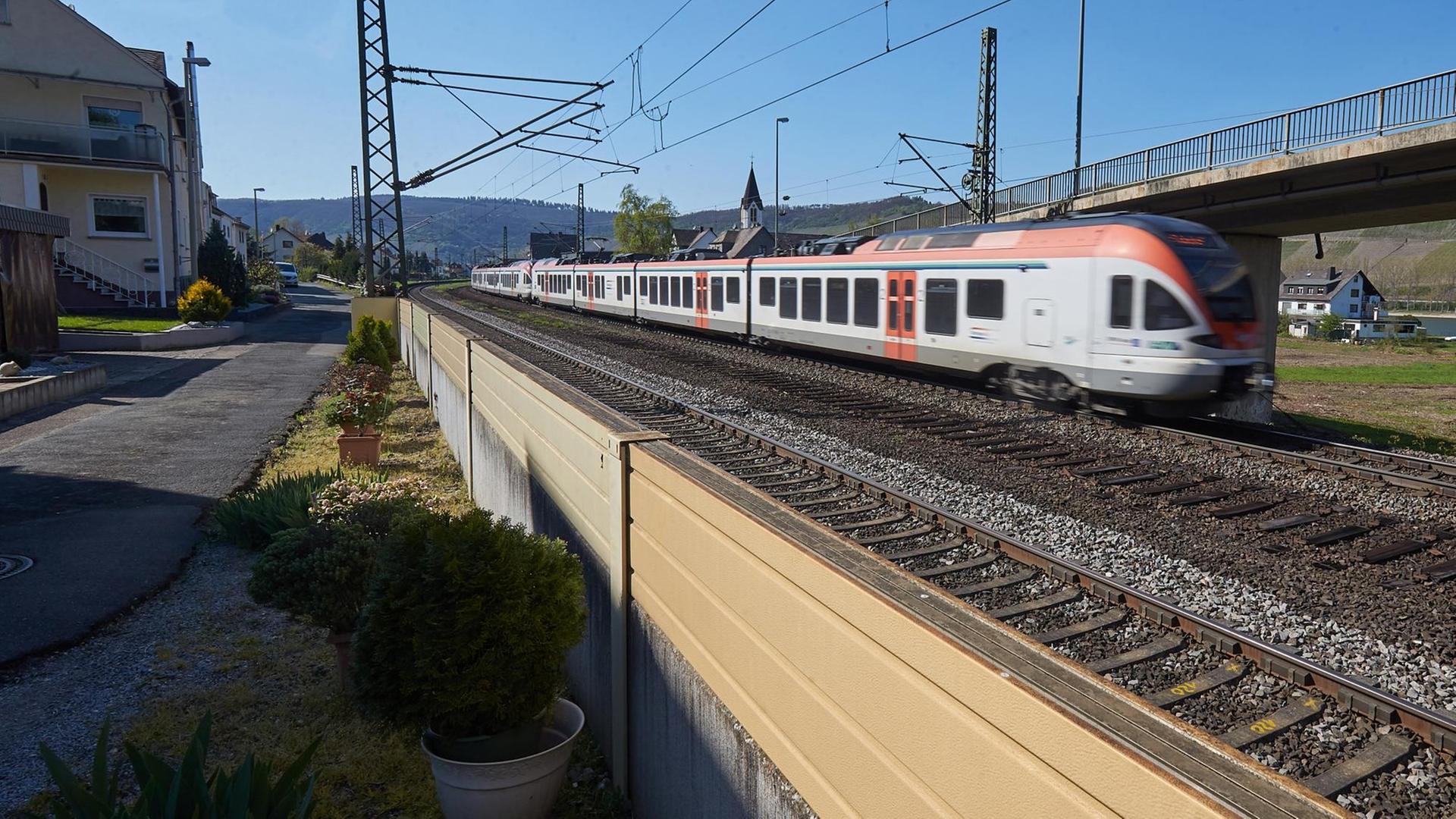 Rheinland-Pfalz, Osterspai: Ein Zug fährt im Rheintal an einer direkt am Gleisbett platzierten niedrigen Lärmschutzwand vorbei.