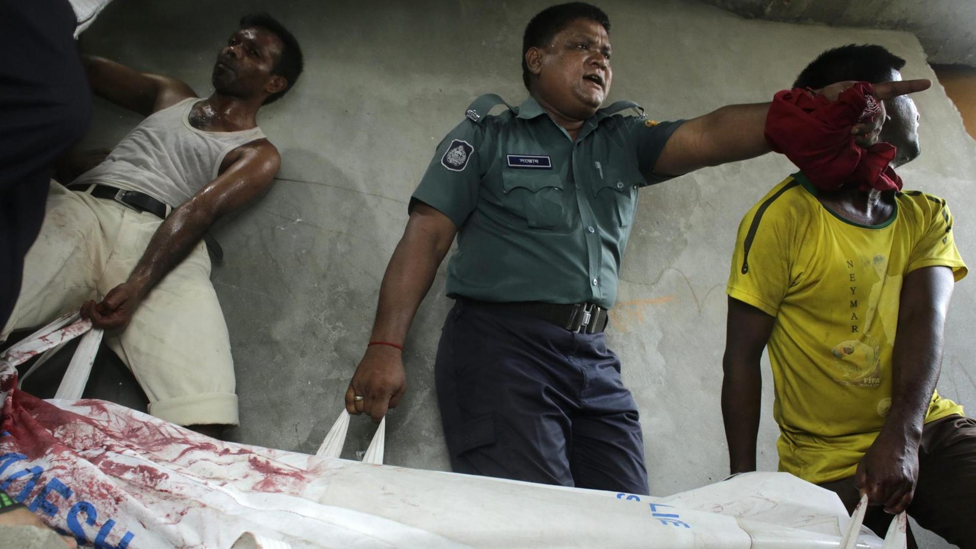 Sicherheitskräfte tragen den Leichnam des Bloggers Niloy Chakrabart eine Treppe hinunter (7.8). Nun wurden drei Verdächtige inhaftiert.