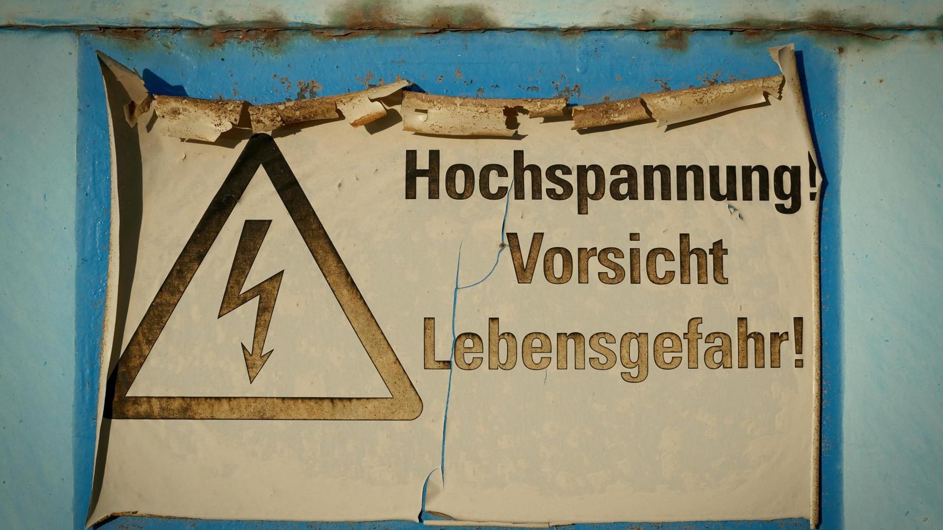 Farbfoto eines verblassten Schildes mit der Aufschrift, "Hochspannung Vorsicht Lebensgefahr"