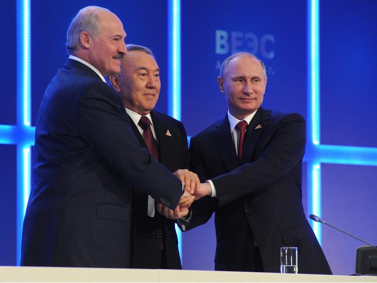 Weißrusslands Präsident Lukaschenko, Kasachstans Präsident Nasarbajew und der russische Präsident Putin legen ihre Hände übereinander.
