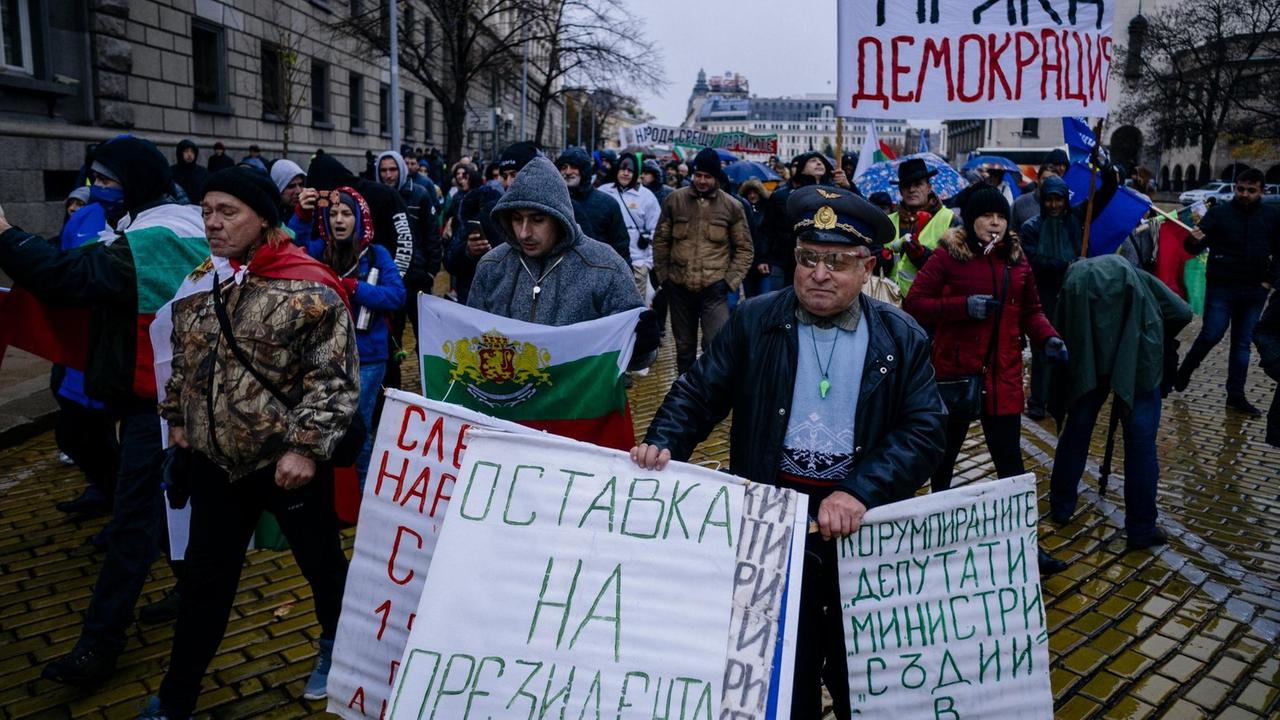 Die Demonstranten laufen eine Straße entlang und halten Transparente in kyrillischer Schrift.