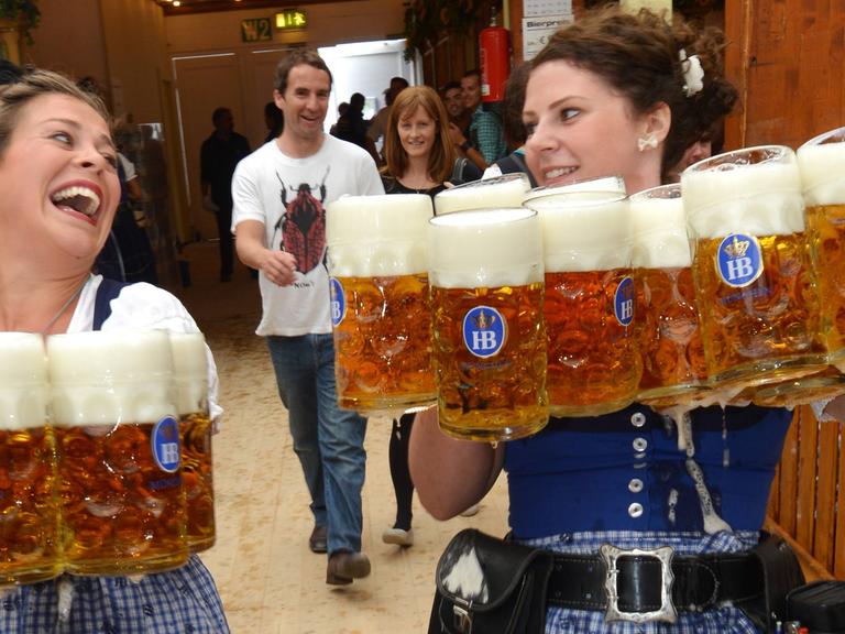 Bedienungen bei der Eröffnung des 180. Oktoberfests am 21.09.2013 in München (Bayern) mit Bierkrügen.