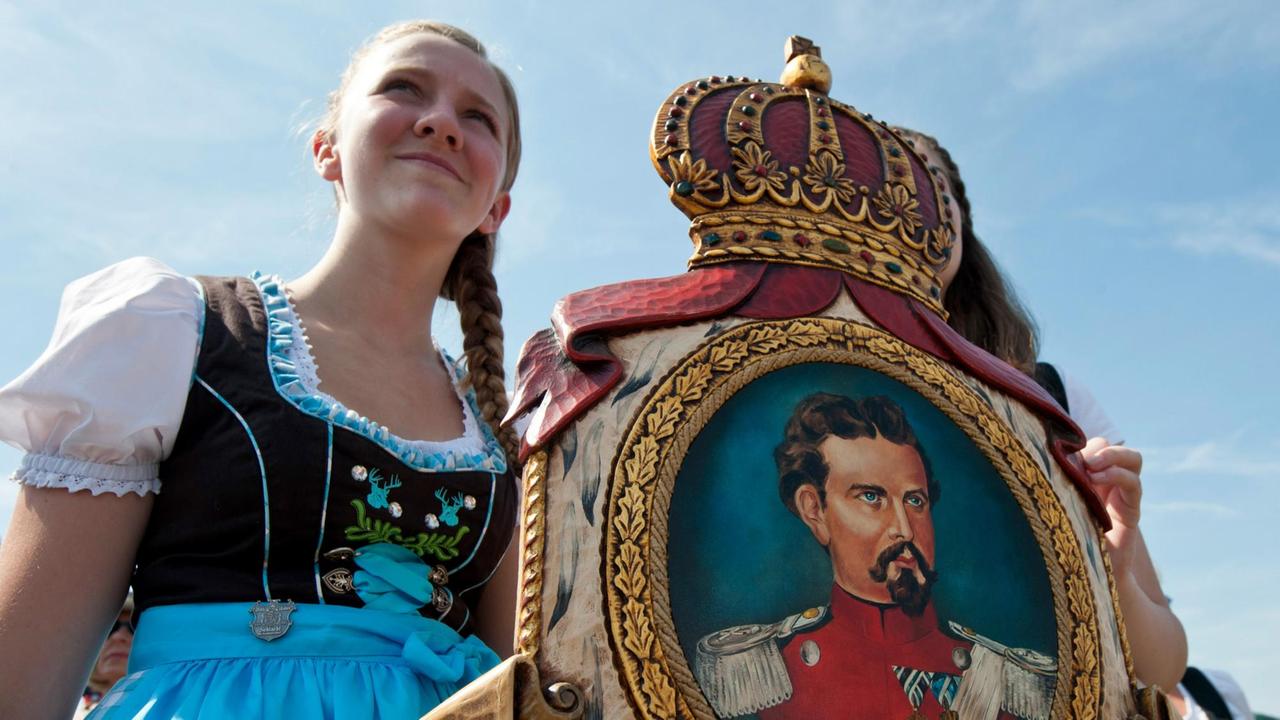 Eine Verehrerin hält eine Holztafel mit dem Bild von König Ludwig II.