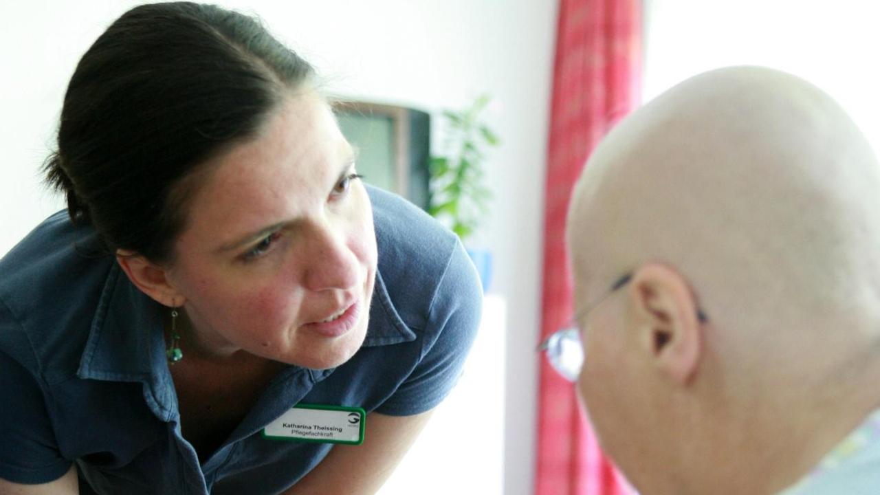 Die Mitarbeiterin des Pflegepersonals in einem Hospiz spricht mit einem sterbenskranken Patienten