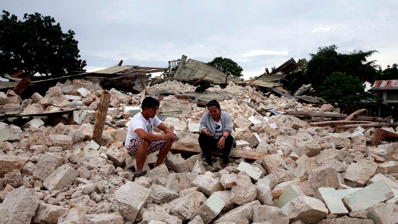 epa03913700 Filipino teacher Hannah Jumang-It, 33, (R) cries next to her brother Mark Dave, 37, (L) as they wait for the retrieval of their father, Necitas Mejorada, 73 a lay minister who was trapped and killed by the rubble of damaged church of Our Lady 
