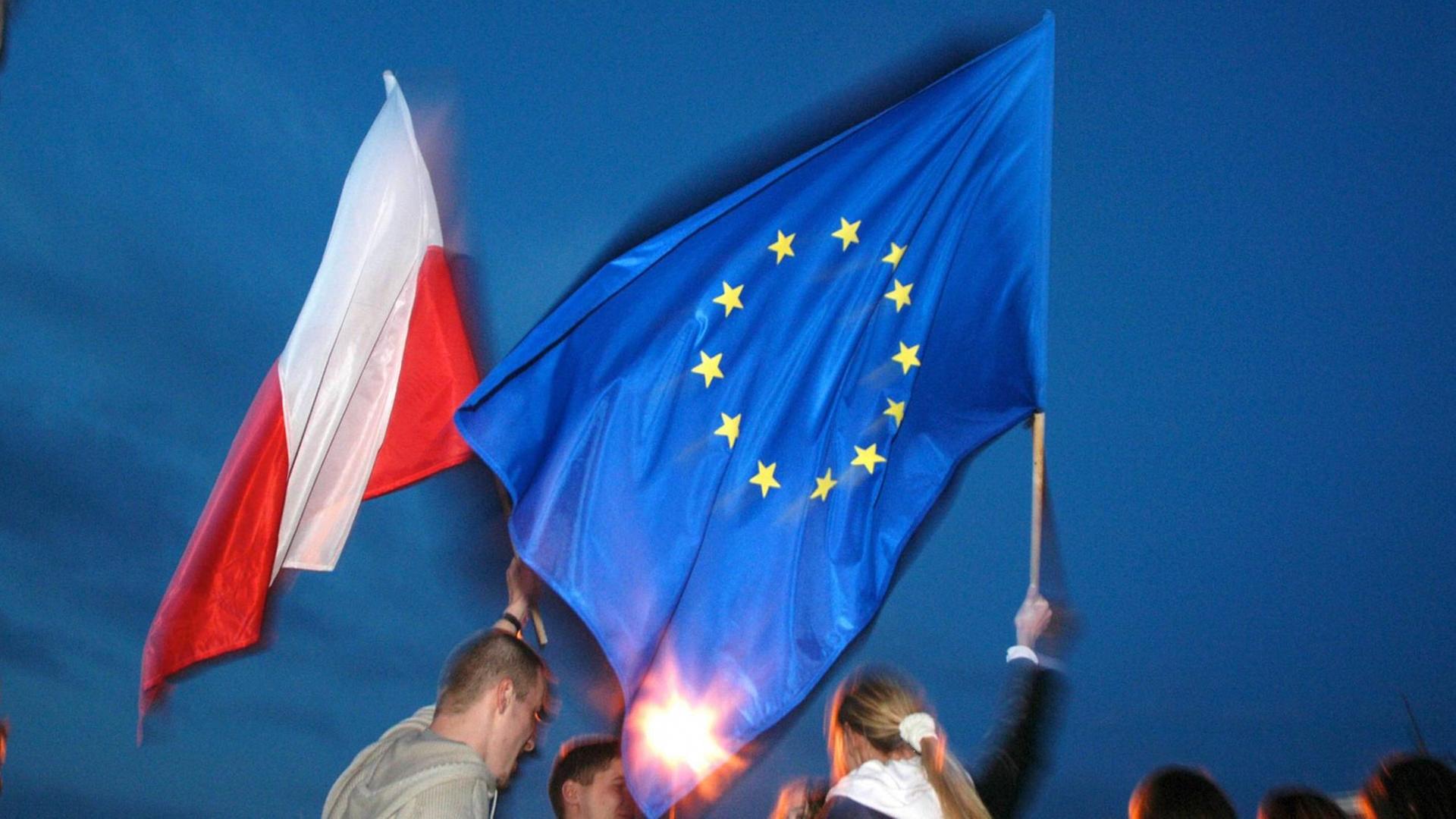 Polnischer Student mit Polen-Flagge in der Haynd, polnische Studentin mit der EU-Flagge in der Hand