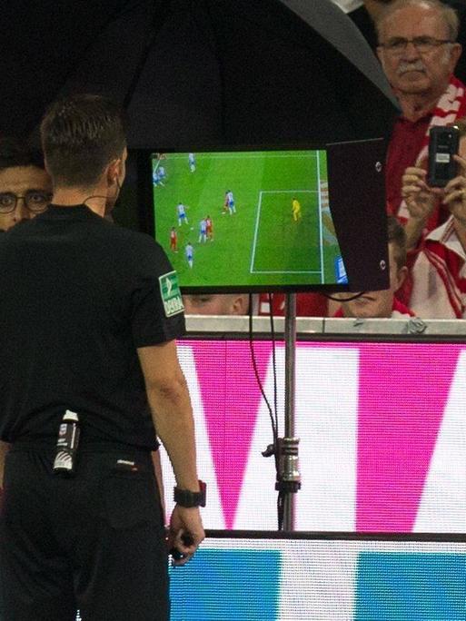Schiedsrichter, Referee, Harm Osmers schaut auf einen Monitor und kontrolliert mit dem Videobeweis pb es sich um ein Foul handelte.