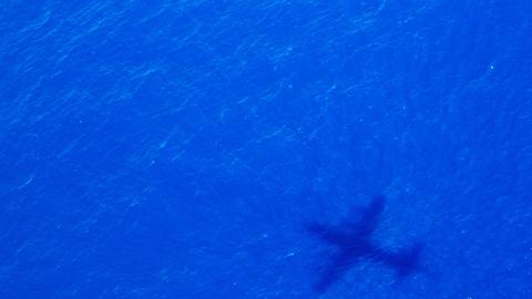 Der Schatten eines Flugzeuges auf blauem Meer
