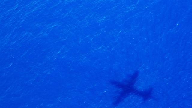 Der Schatten eines Flugzeuges auf blauem Meer