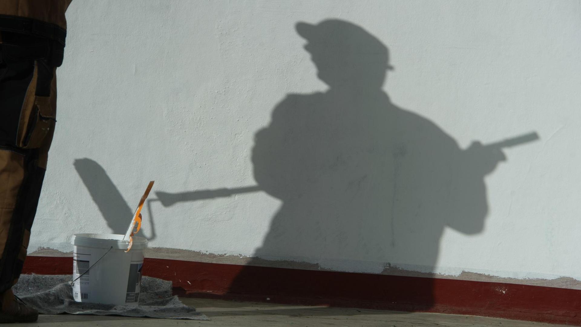 Ein Maler wirft auf einer Baustelle einen Schatten.