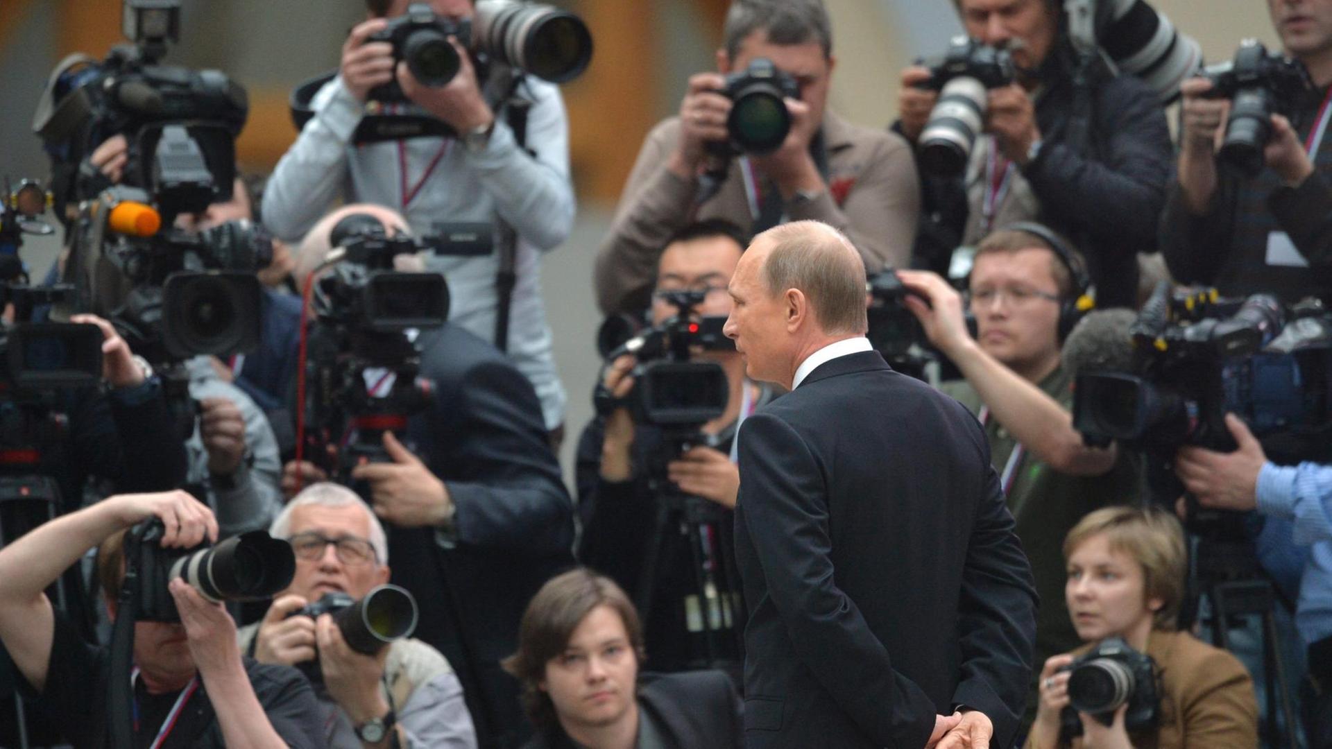 Der russische Präsident Vladimir Putin umrahmt von Fotografen.