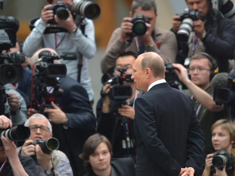 Der russische Präsident Vladimir Putin umrahmt von Fotografen.